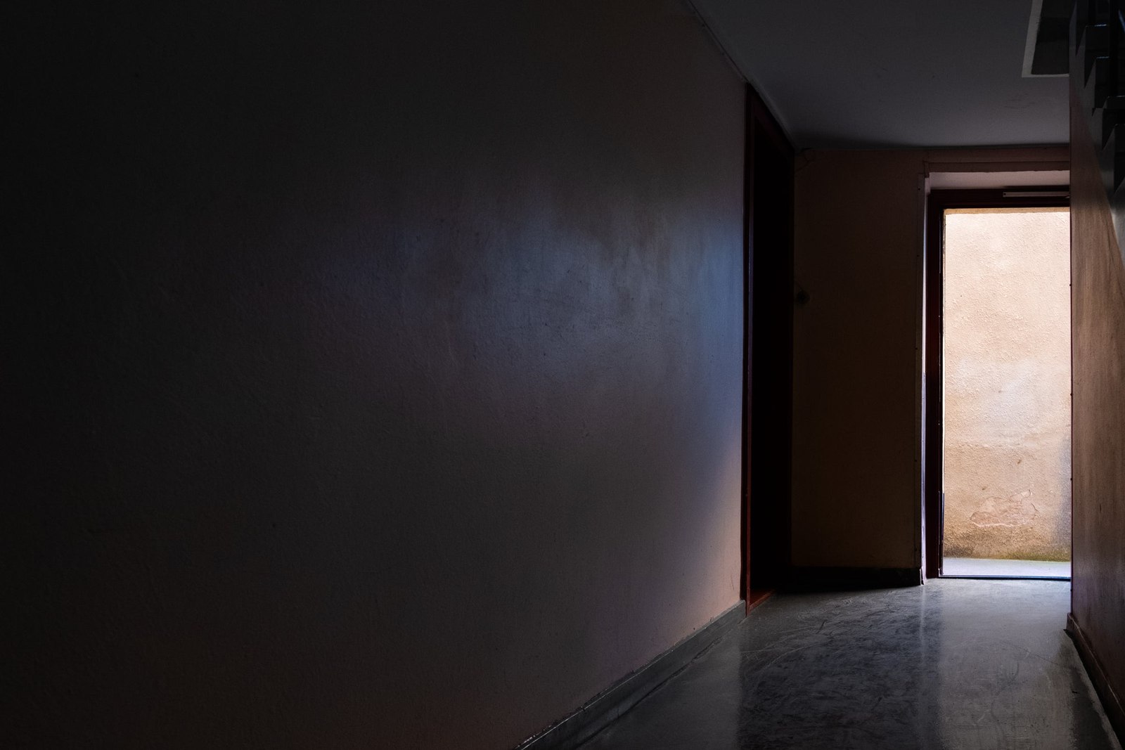 A bright doorway casting light into a dark empty room
