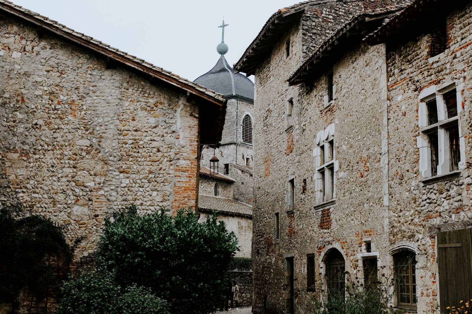 Stone courtyard framed by old buildings and greenery