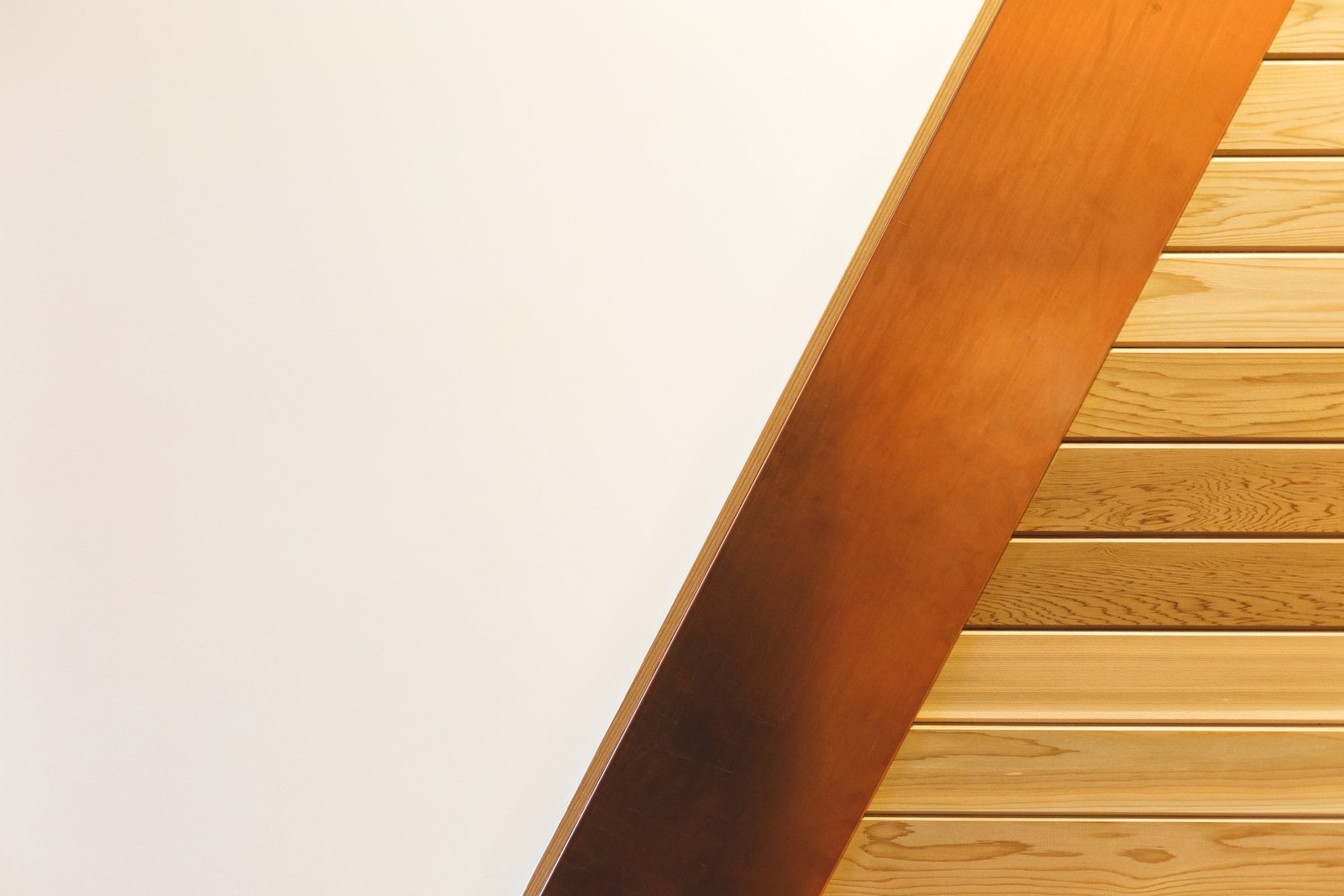 Pale wall meeting a warm metal-toned edge and timber surfaces