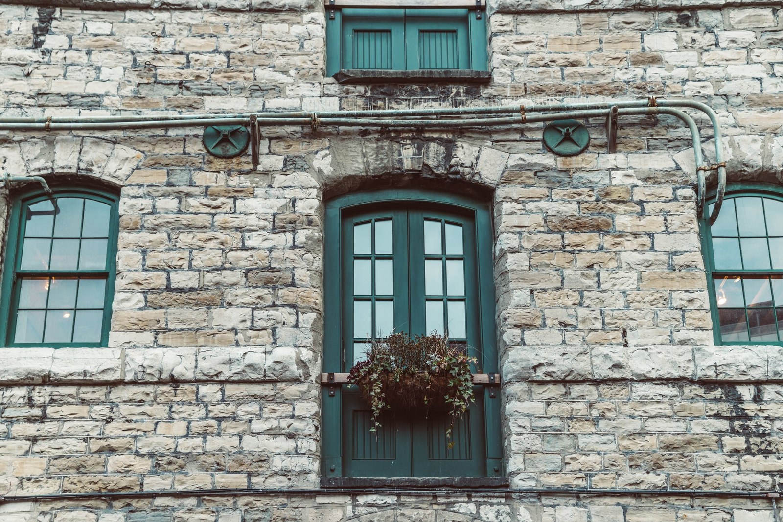 Green door and windows set into a rough stone building frontage