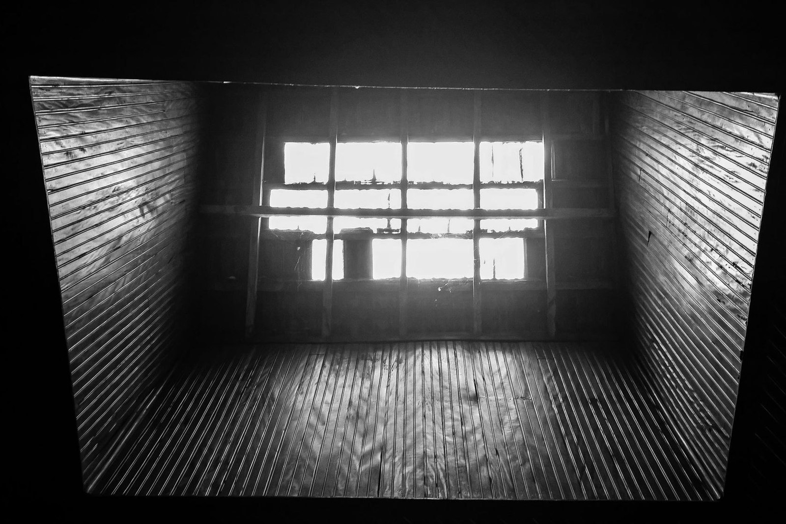 Strong window shadows across the walls of a dark timber interior